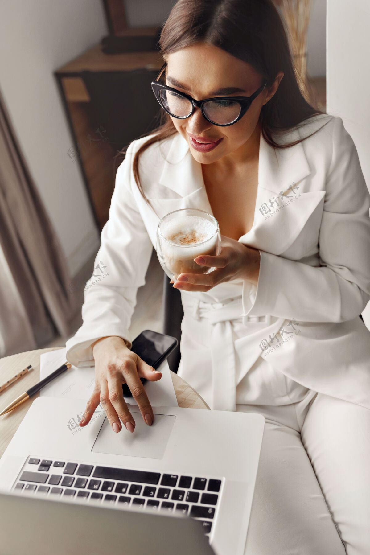 商务美丽的年轻女子坐在客厅里 一边用笔记本电脑工作 一边喝着咖啡微笑小型经理