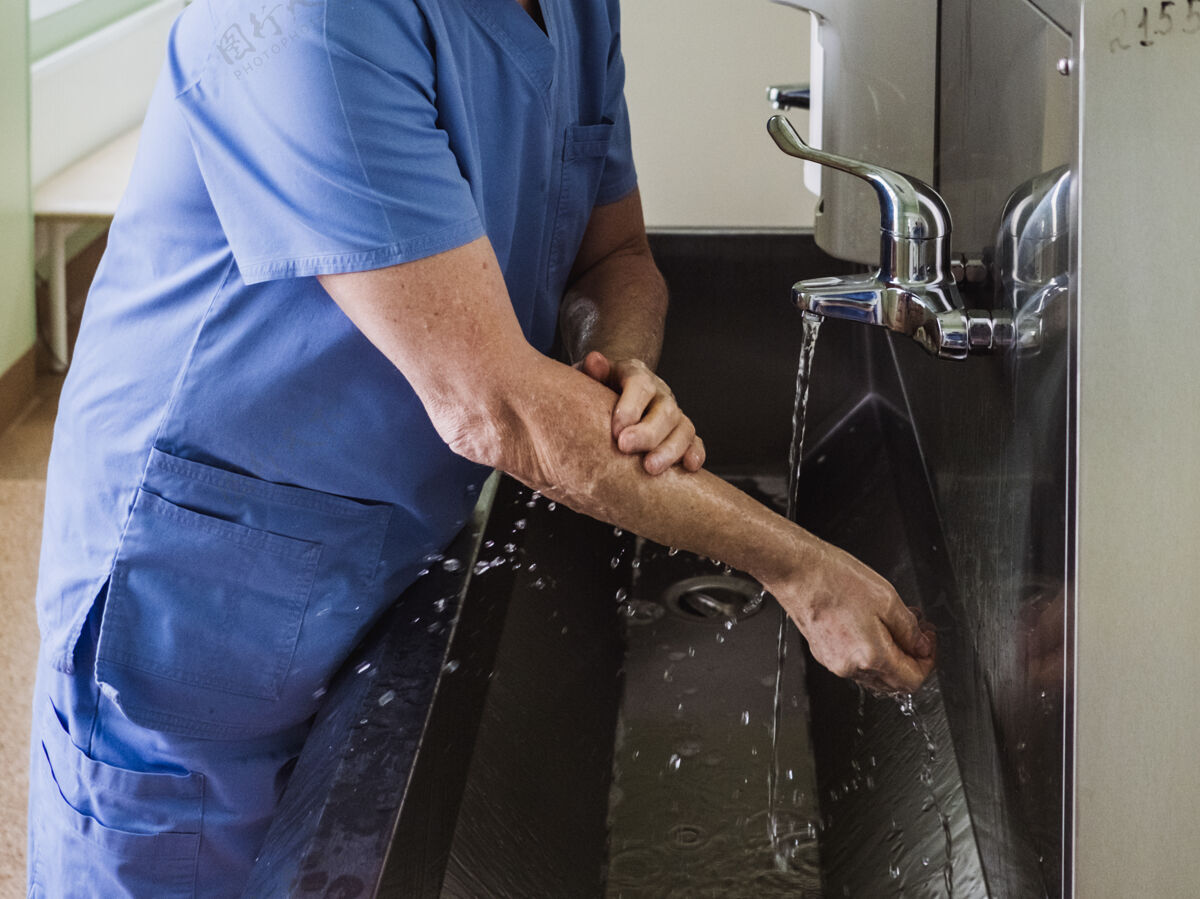 消毒剂一位男医生用肥皂在不锈钢的自来水里彻底洗手水槽必要时消毒措施喷射药品清洁