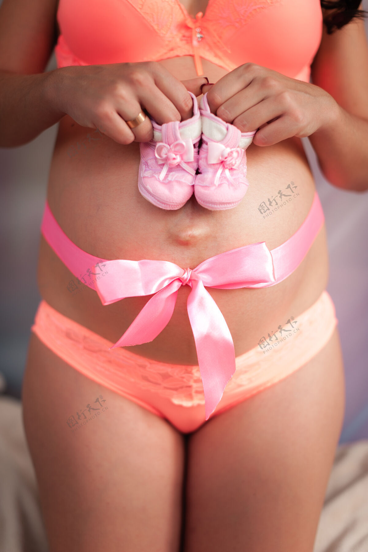 身体一个肚子上带着蝴蝶结的怀孕女孩拿着孩子们的袜子妈妈父母肚子