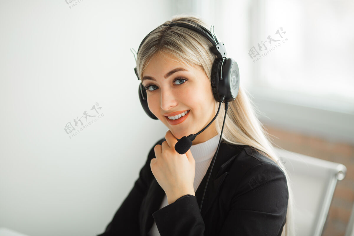 行政漂亮的年轻女子穿着西装在办公室的桌子旁戴着耳机通信中文商务