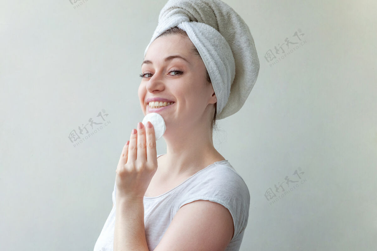 自然头上戴着毛巾的微笑女人的美丽肖像 柔软健康的皮肤 用隔离在白色背景上的化妆棉卸妆棉年轻感官