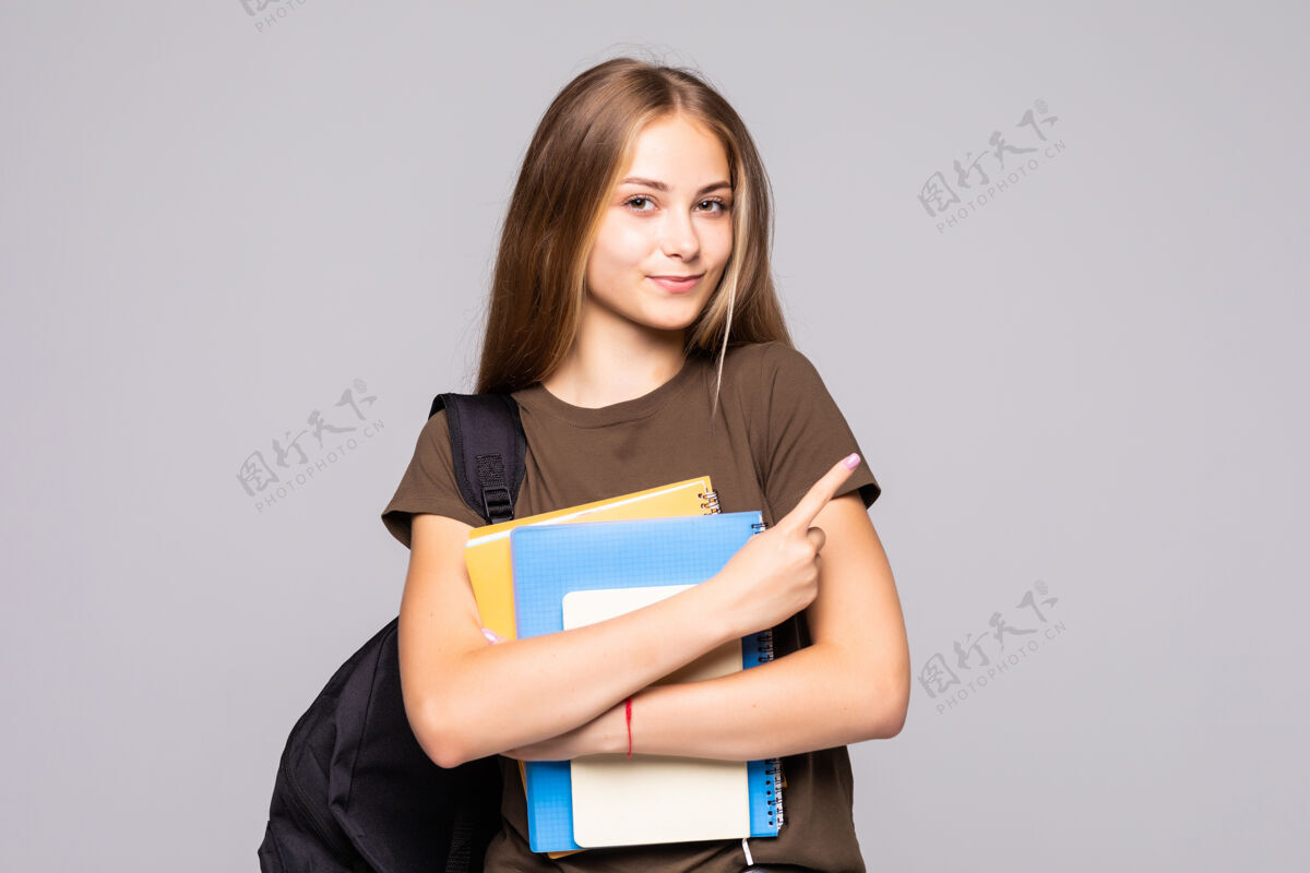 人可爱的年轻黑发学生的肖像拿着练习本孤立在白墙上年轻人女人女孩