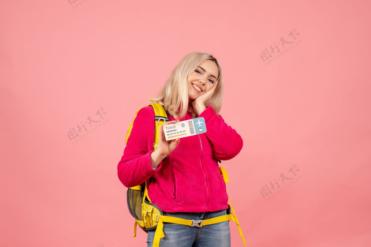 票正面是微笑的旅行者 穿着休闲服 背着背包 在粉红色的墙上拿着票成人女士时尚