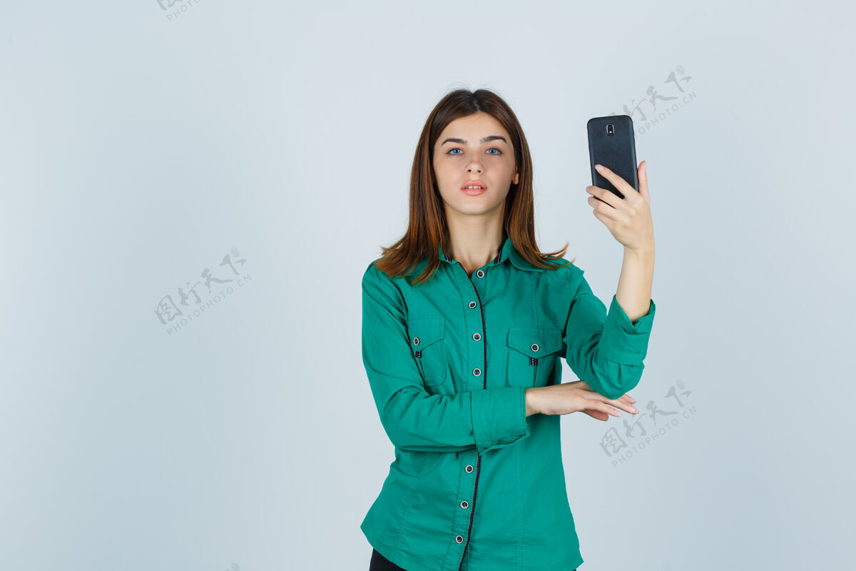 秋天照片中的年轻女士手持手机 身穿绿色衬衫 表情严肃 正对着前方持有成人孤独