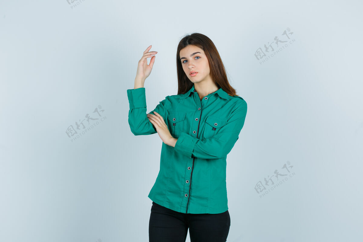 女性年轻女性穿着绿色衬衫和裤子举手摆姿势 看起来很漂亮正面图而帽子女孩