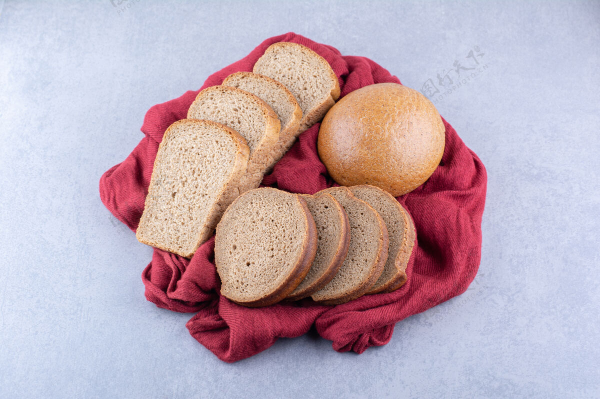 面包棕色的面包片和一个面包放在大理石表面的布片上面包酵母烘焙食品
