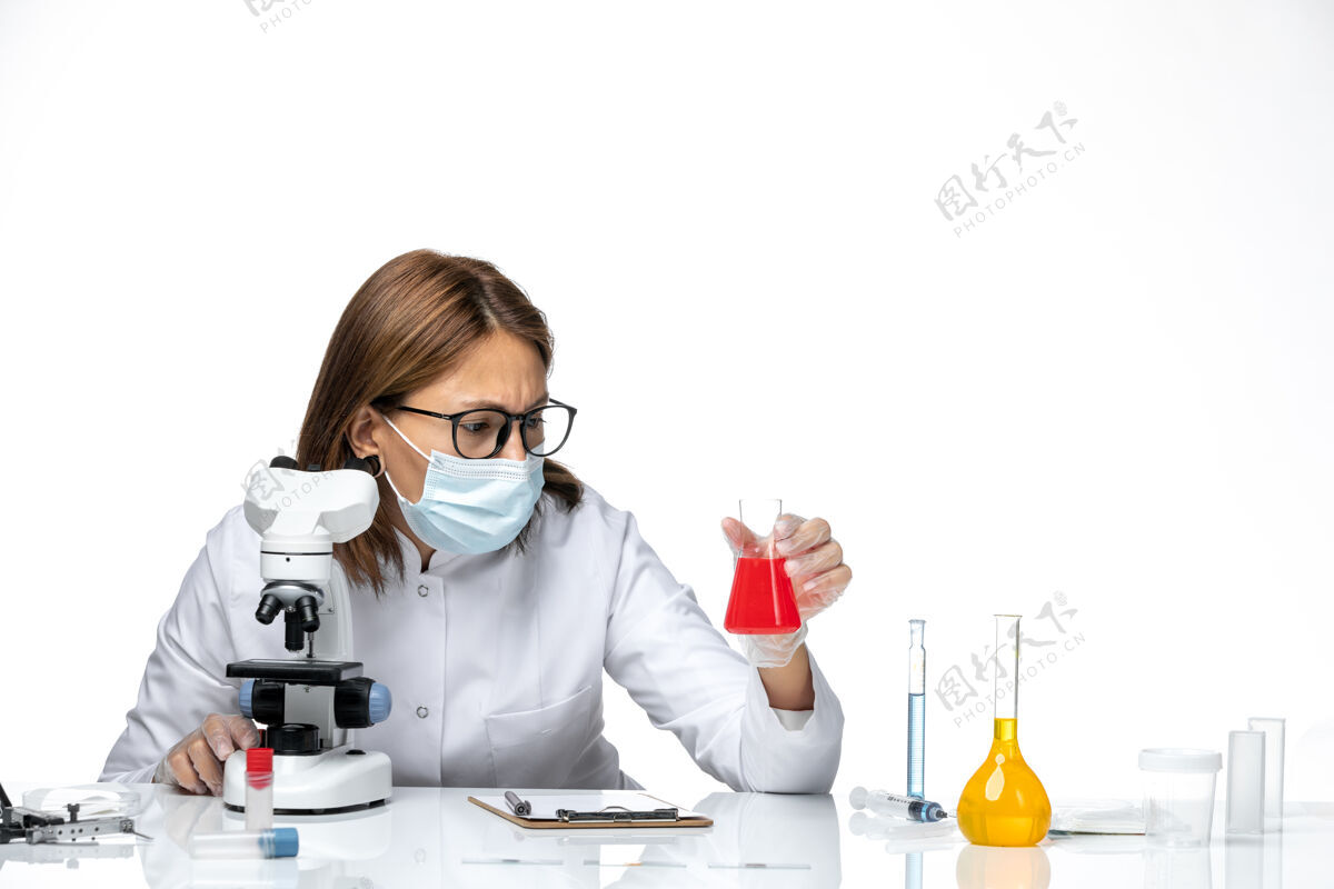 使用前视图：女医生穿着白色医疗服 戴着面罩 在白色空间使用显微镜药品医疗显微镜