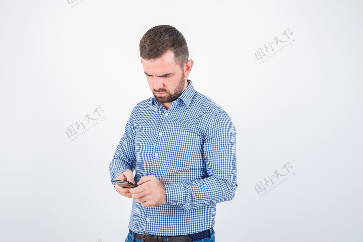 创意年轻的男人穿着衬衫 牛仔裤在手机上聊天 神情沉思 俯瞰前方正面男人人