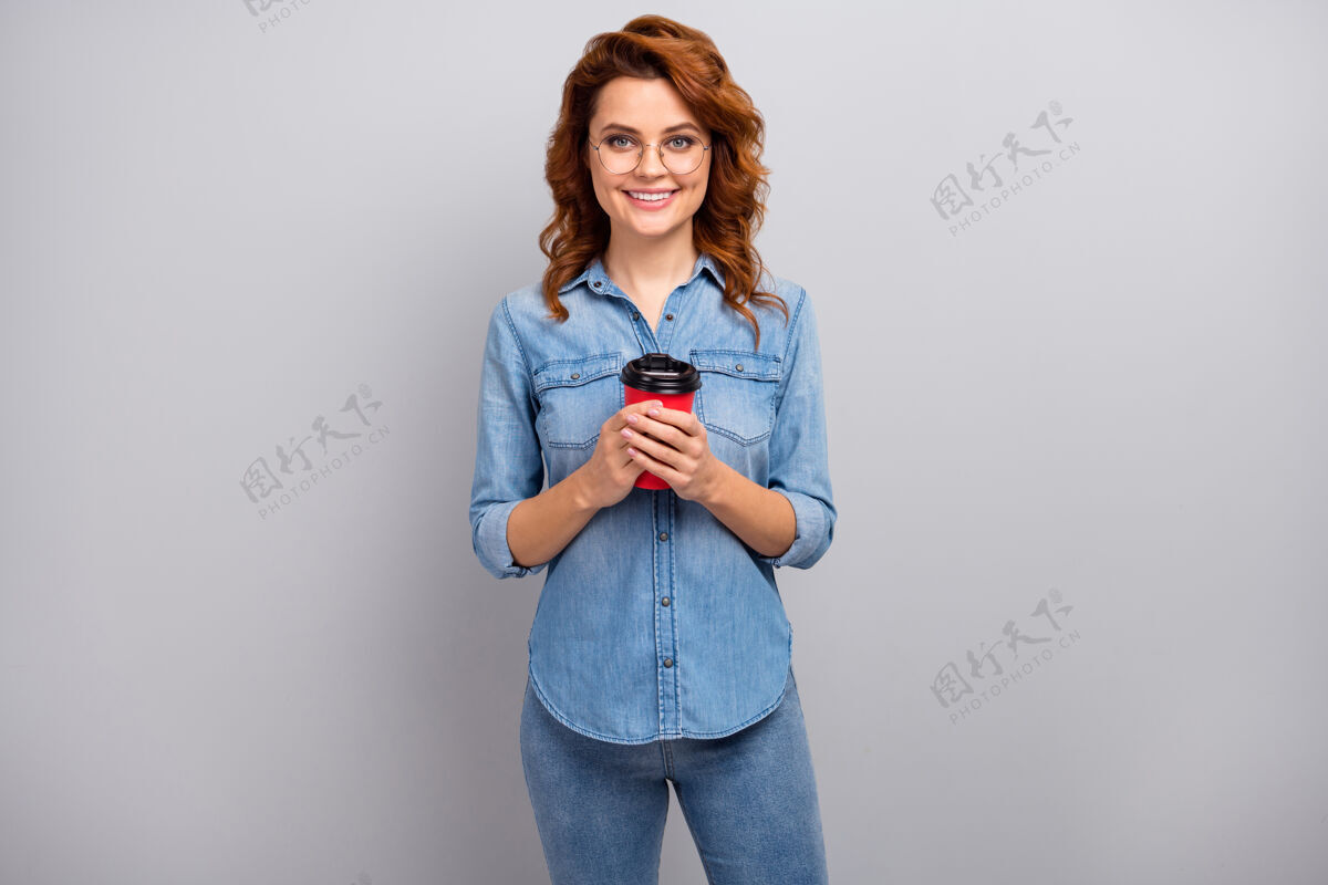 外卖积极开朗的女性自由职业者企业家的肖像拿着杯拿铁咖啡享受工作休息穿好看的衣服隔着灰色的墙马克杯休息女孩