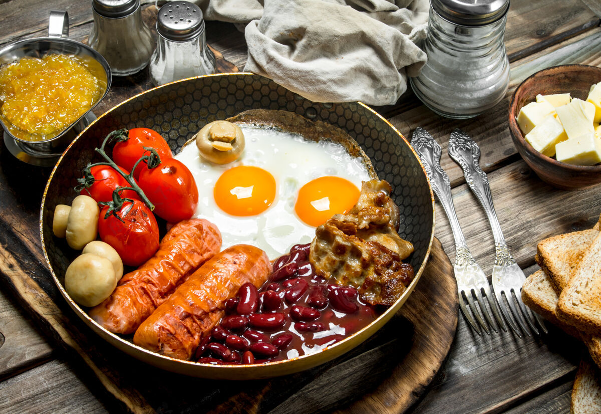 平底锅英语早餐油炸的鸡蛋 香肠 培根和红豆罐头放在乡村的桌子上桌子英式烘焙