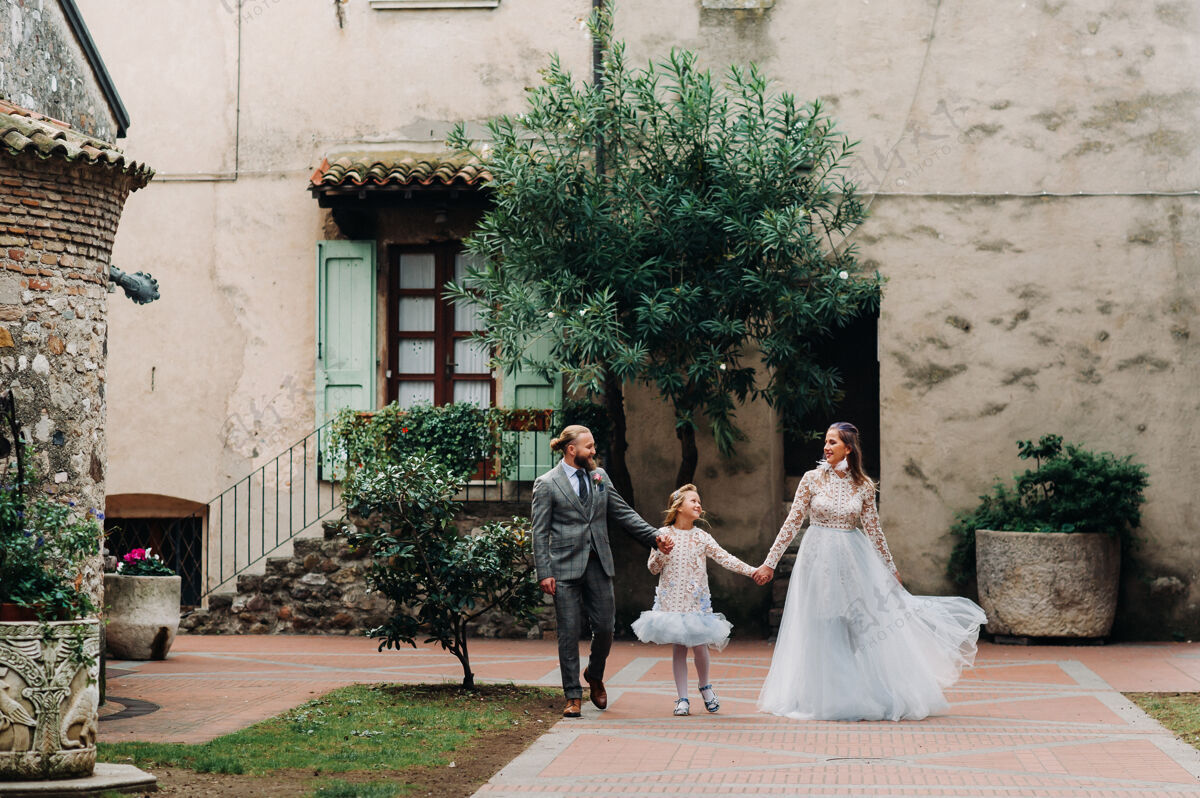 女儿一个幸福的年轻家庭走过意大利的锡尔米翁古城爱情家庭拍摄