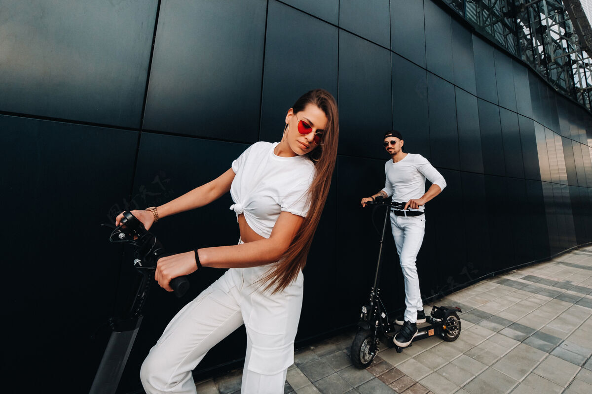 电力一个女孩和一个男孩骑着电动滑板车在城市里走来走去 一对恋人骑着滑板车休闲踢摩托车骑