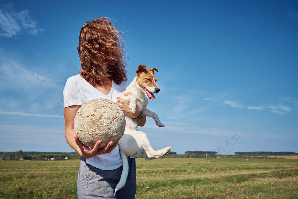 朋友女人在夏天的户外和她的狗玩得很开心与宠物的友谊主人风卷发家庭