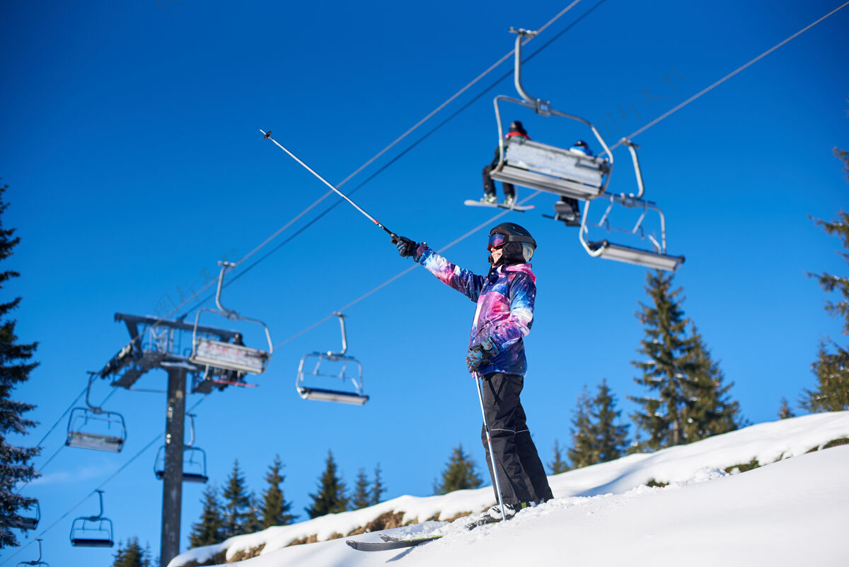 设备快乐的女子滑雪者站在雪覆盖的山坡滑雪电梯附近寒假的晴天总览度假胜地旅游山脊