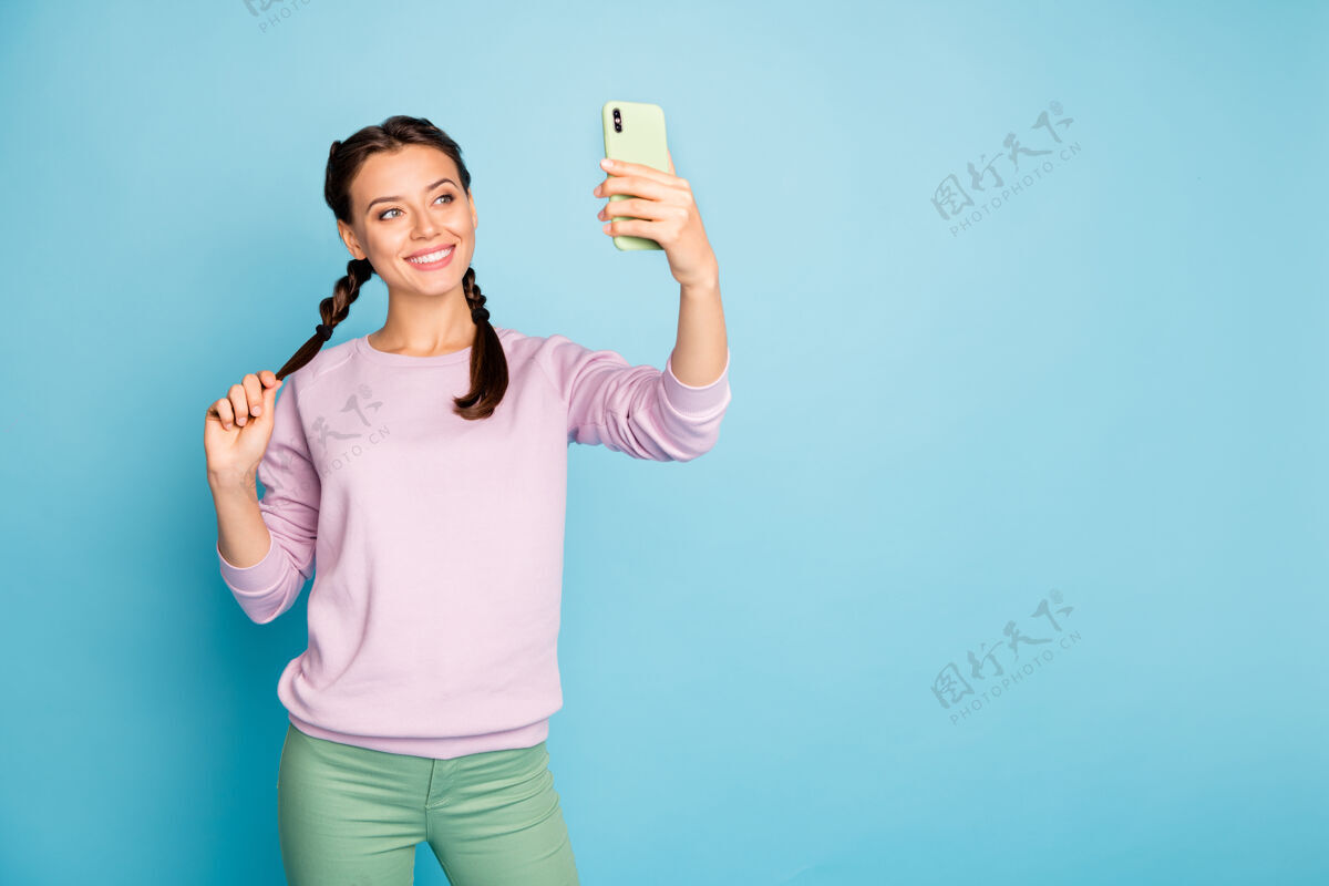 少女美女手持电话拍照搞笑自拍网上博客翻译视频通话穿休闲粉色毛衣绿色长裤孤立蓝色美丽裤子电话