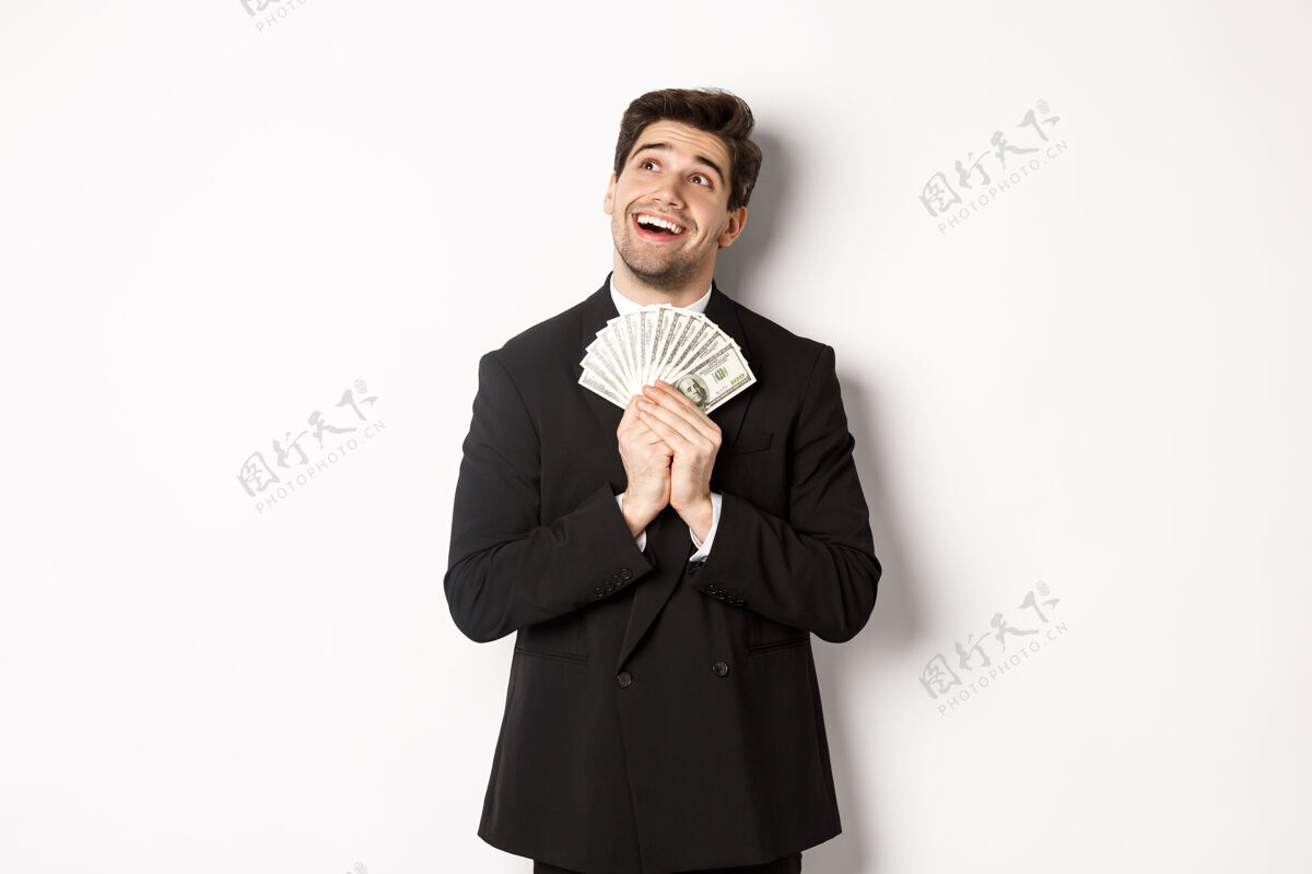 男人一个穿着黑色西装 拿着钱 望着左上角的帅气梦幻男人的形象办公室就业模特