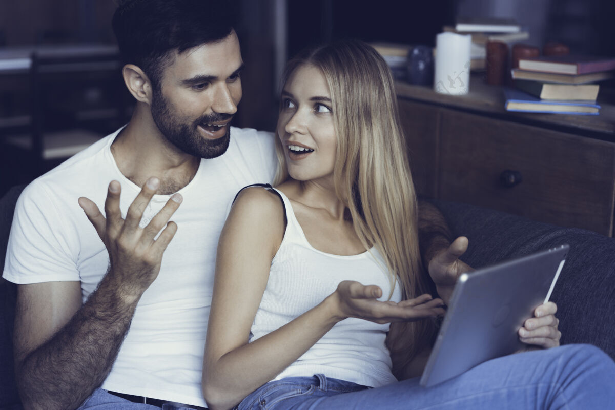 情侣恋爱中的幸福夫妻在家里的平板电脑上冲浪房子手表肖像