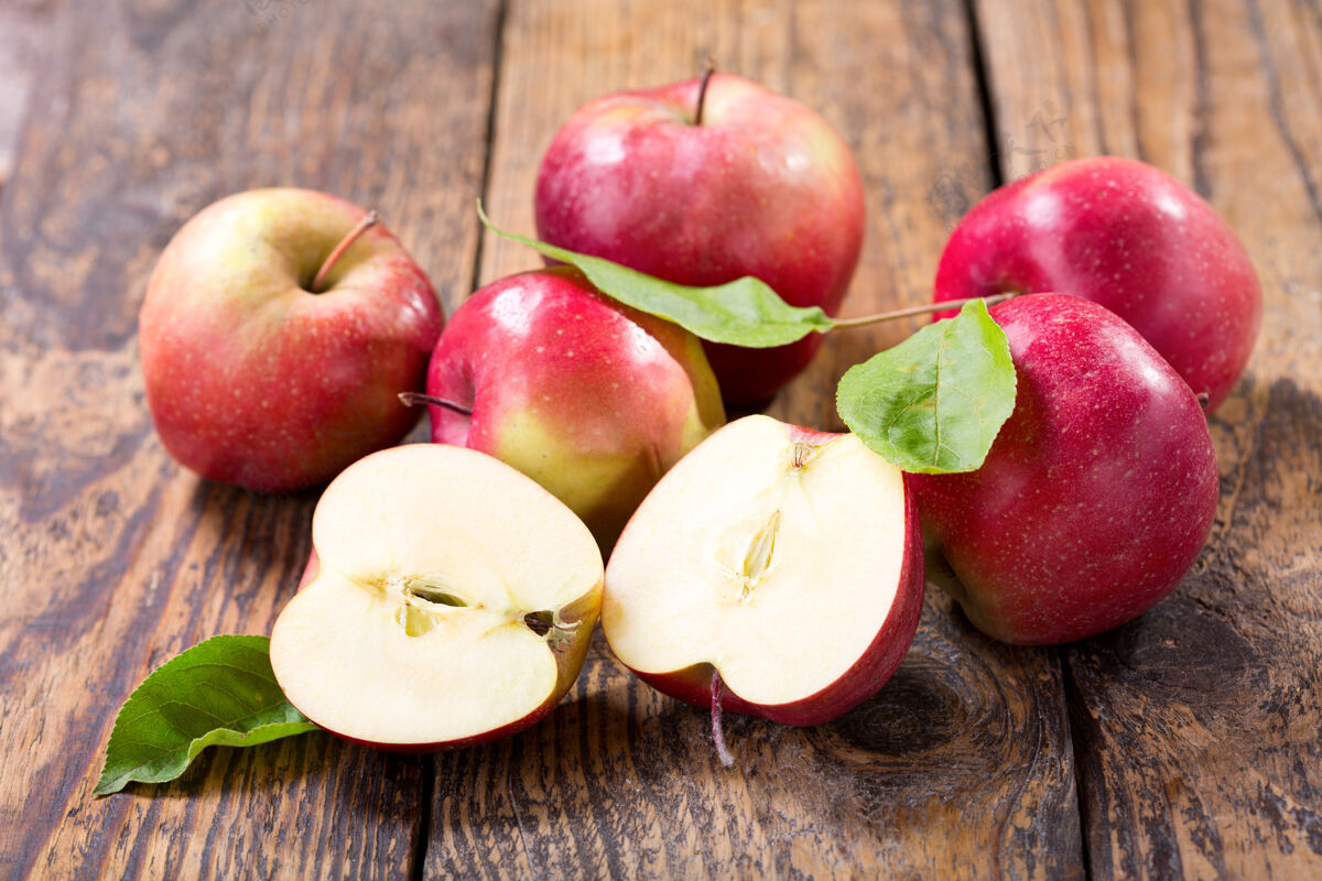 自然木桌上放着新鲜的苹果和树叶多汁甜水果