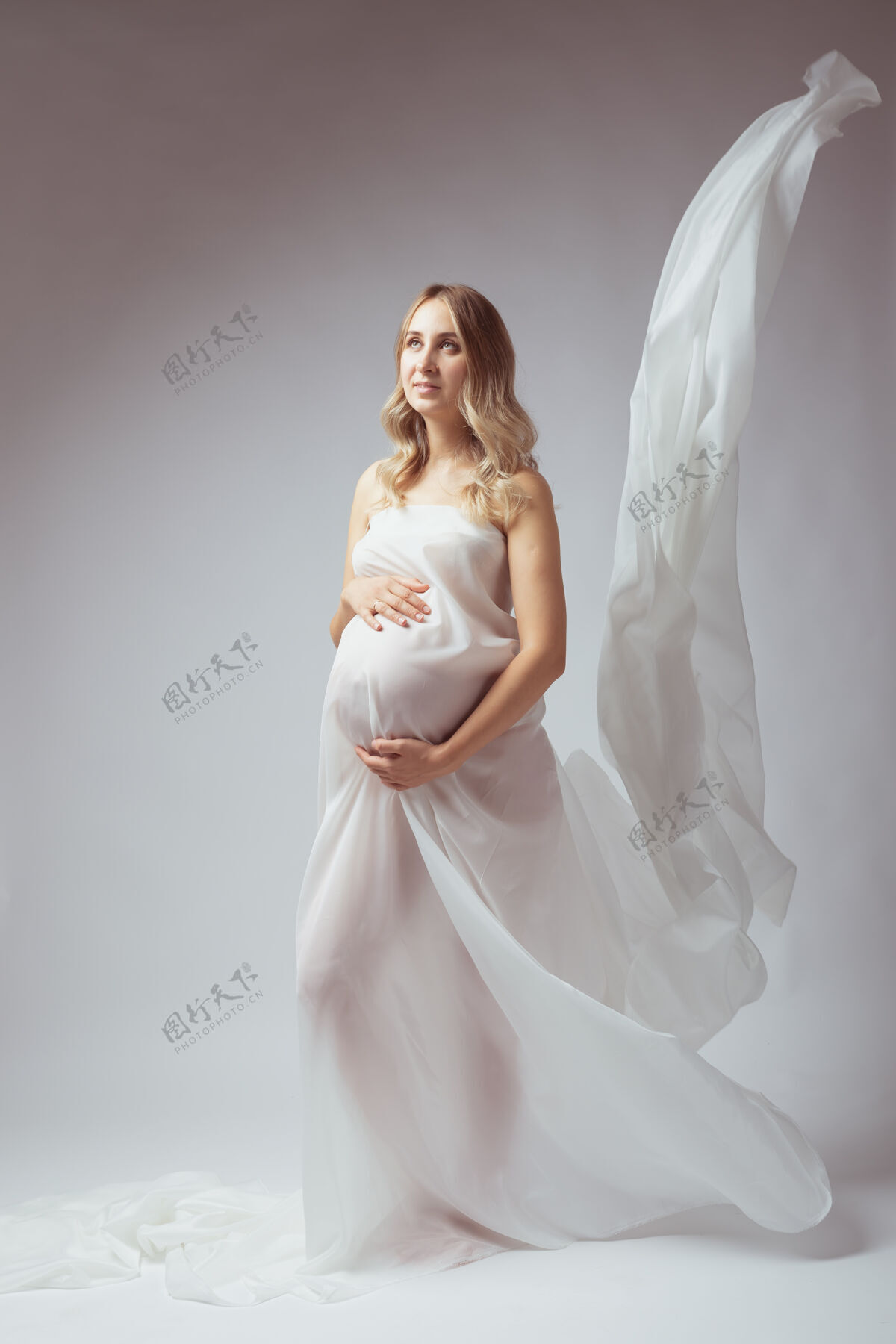 年轻穿着白色飞舞布料站着的孕妇飞行母亲怀孕
