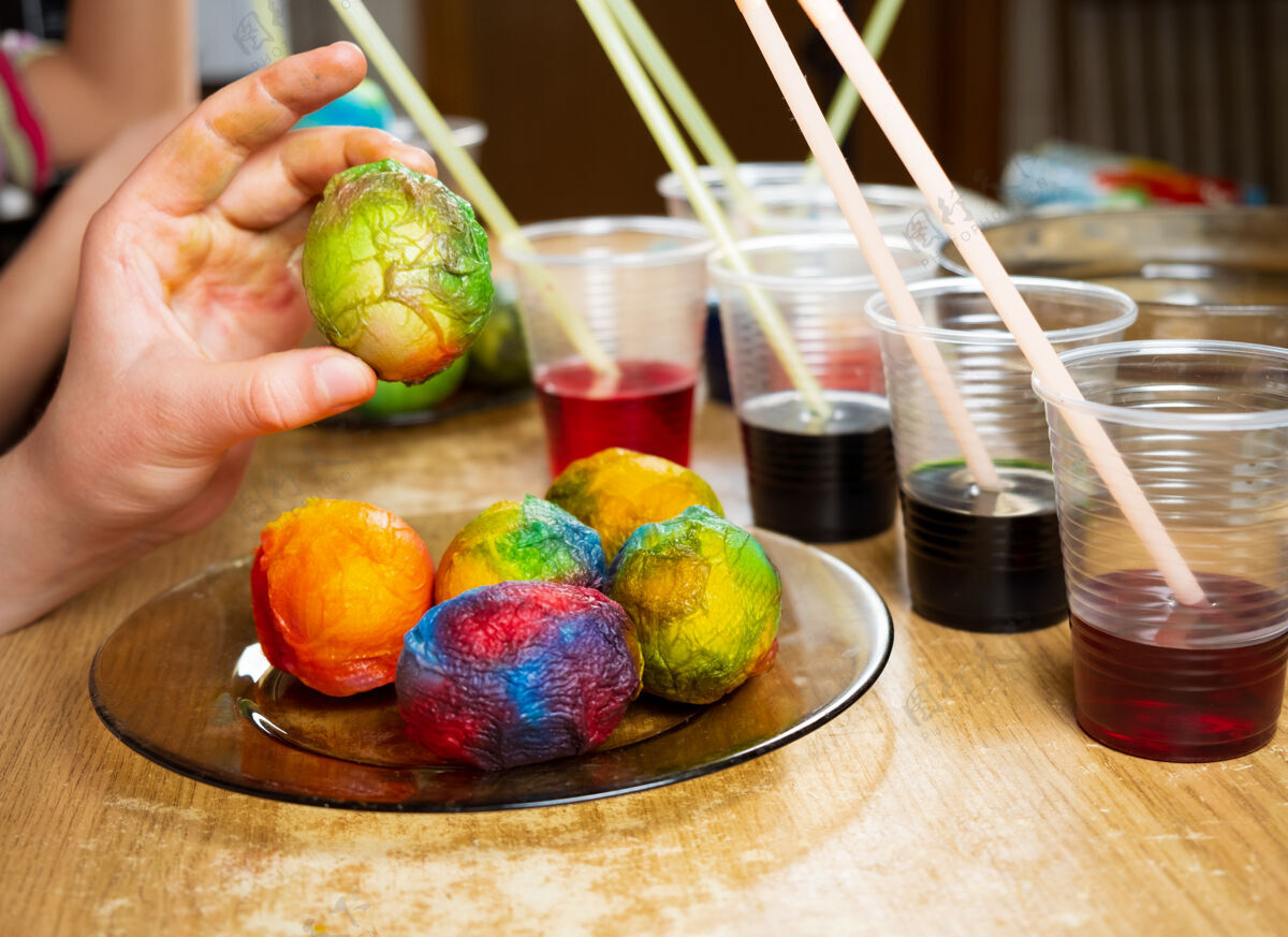 煮沸特写镜头的手 孩子们使用染料和绘画的白煮蛋 而准备复活节传统准备油漆
