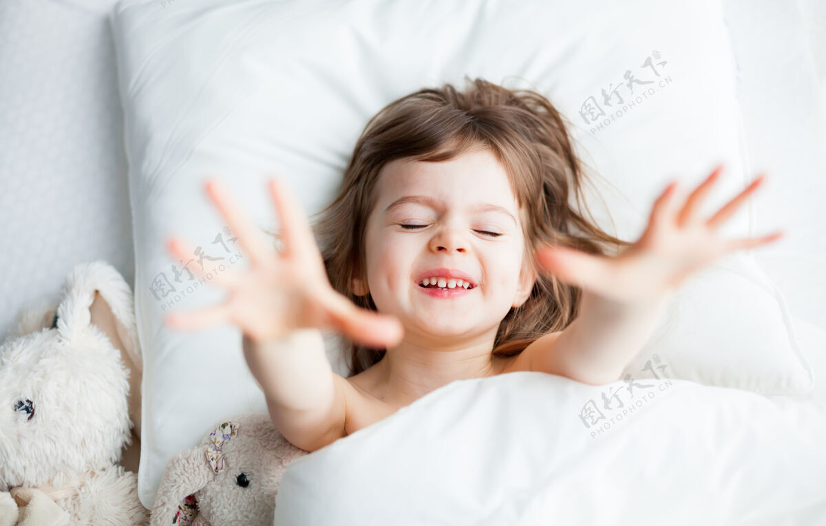 孩子可爱的小女孩醒来时伸出手梦想甜蜜微笑
