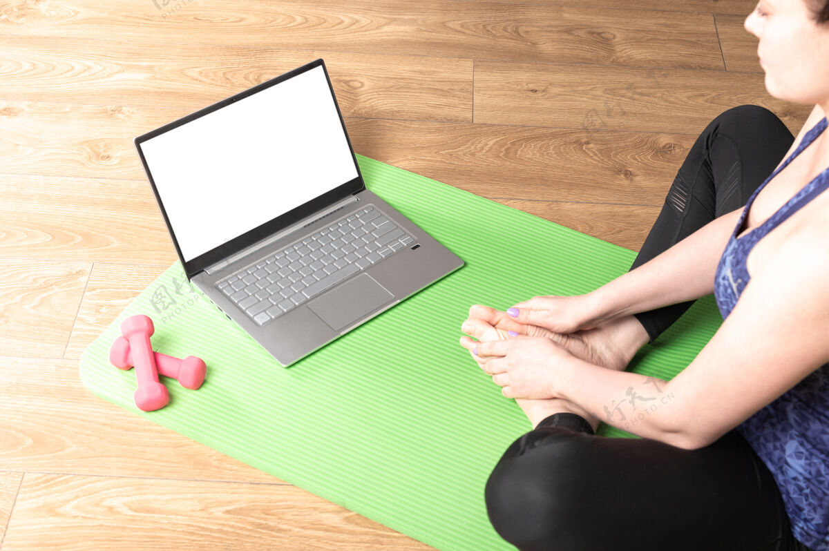个人在家里练习冥想和瑜伽的女人在一台笔记本电脑上 模拟白色的空白屏幕技术锻炼体操