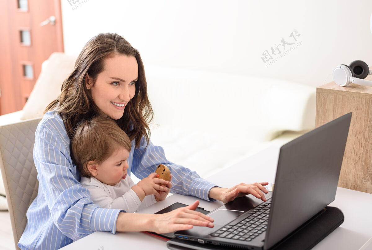 生活方式快乐的母女坐在笔记本电脑旁 远程工作在家 做妈妈 休产假学习房子计算机