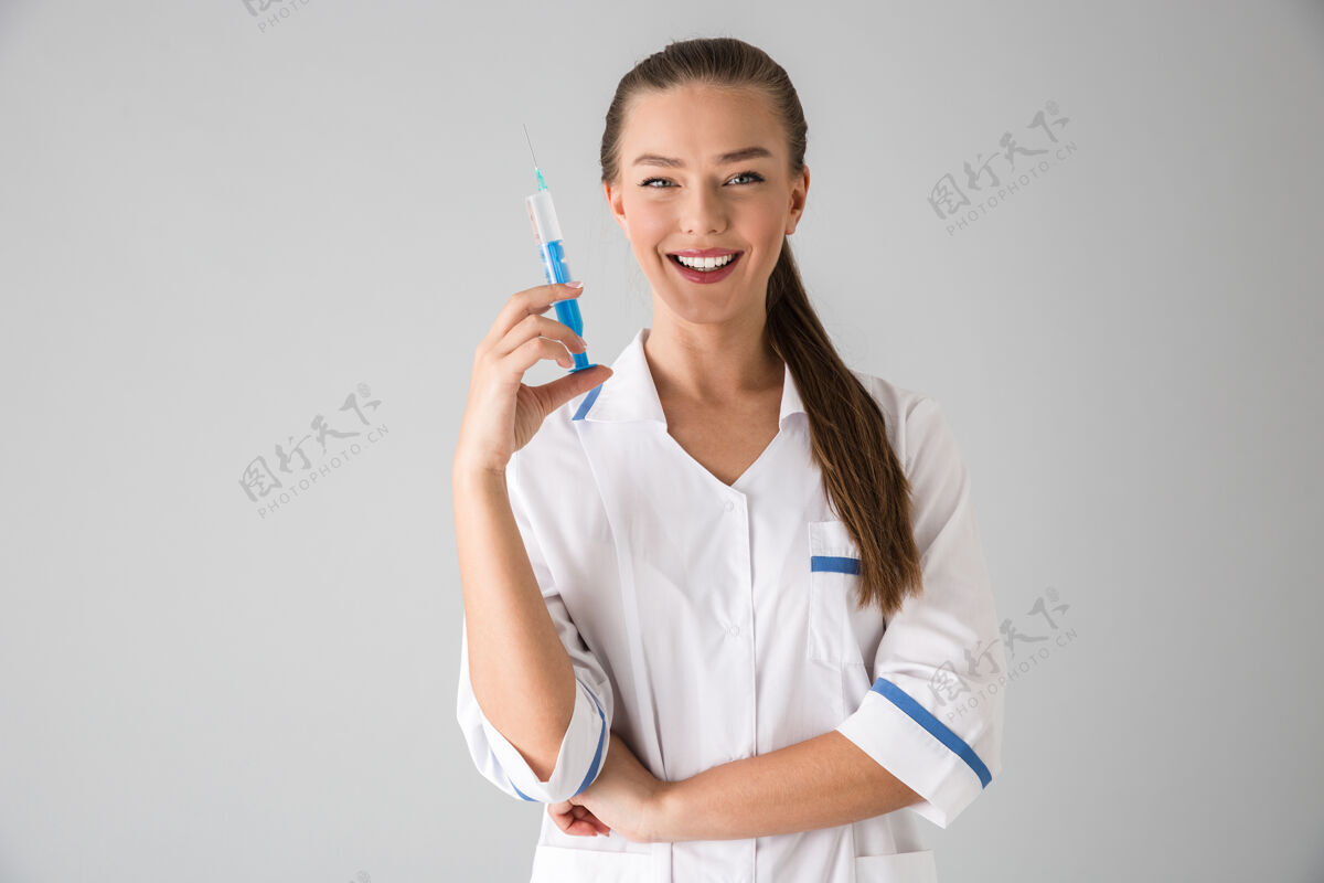 制药一位年轻漂亮的美容师医生拿着注射器隔着灰墙 被隔离在外嘴唇医学医生