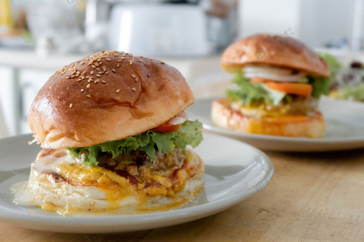 美国两套汉堡包放在木制餐桌上的盘子上快餐不健康牛排