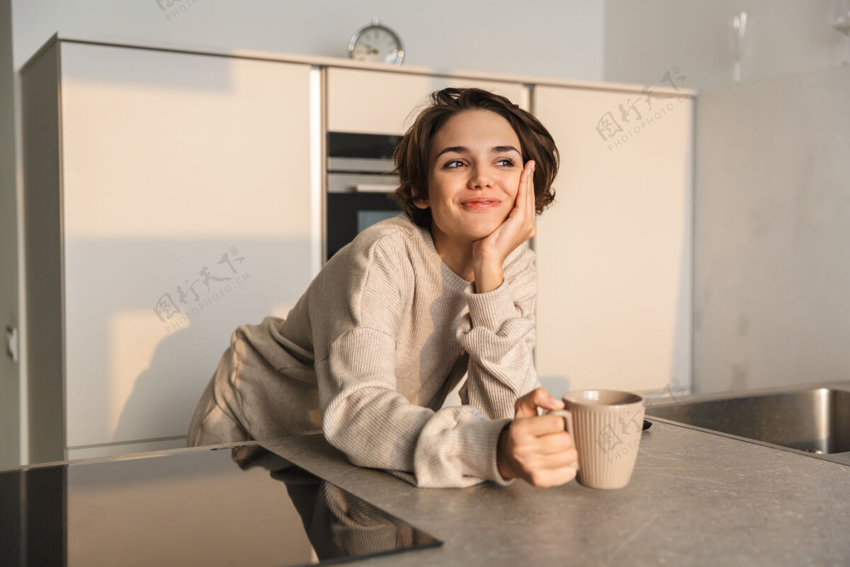 马克杯微笑的年轻女子早上在厨房喝茶举行早餐咖啡
