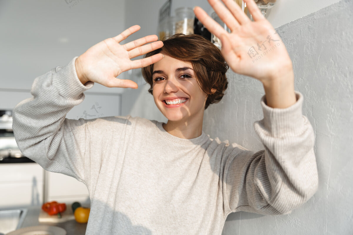 吸引力快乐的年轻女子站在厨房里伸出双手损失零食白种人