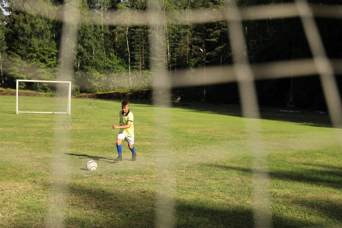 球穿着黄色t恤的帅哥足球运动员在足球场上玩球领域足球草地