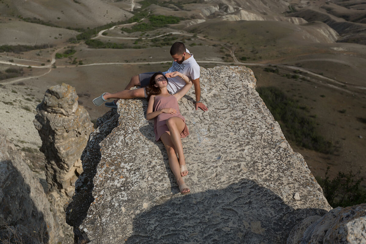 年轻在阳光明媚的天气里 一个女人躺在一块灰色的石头上 在山上的一个自然山谷里男性女人浪漫