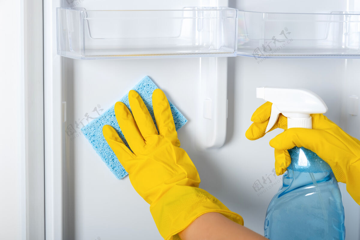 家务一个女人的手戴着黄色的橡胶防护手套和蓝色的海绵在清洗冰箱货架.清洁服务 家庭主妇 日常事务家务.喷雾窗户和玻璃表面清洁剂清洗消毒内部