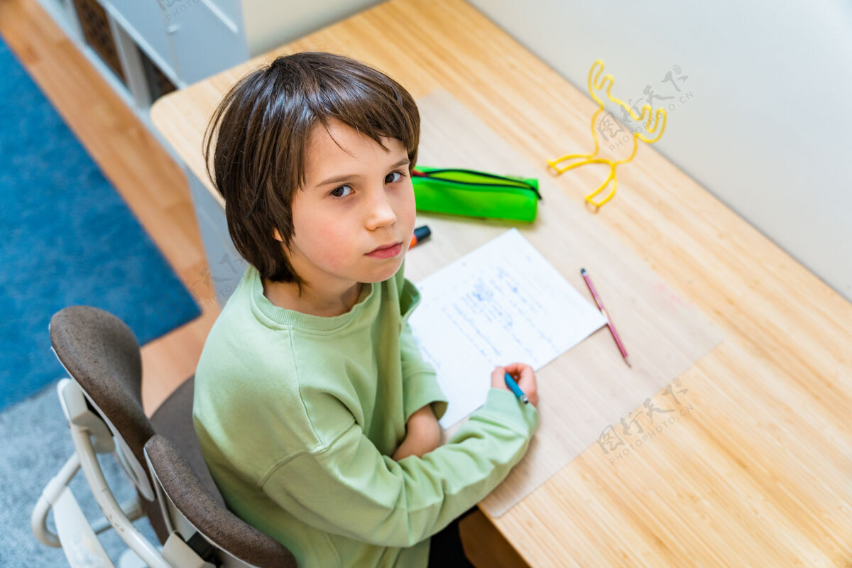 男孩小男孩坐在家里的桌子旁做作业练习学生家庭作业