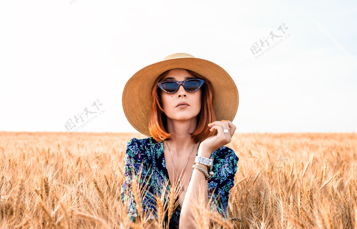 田野时髦的女孩戴着帽子 背景是麦穗女人太阳镜女孩