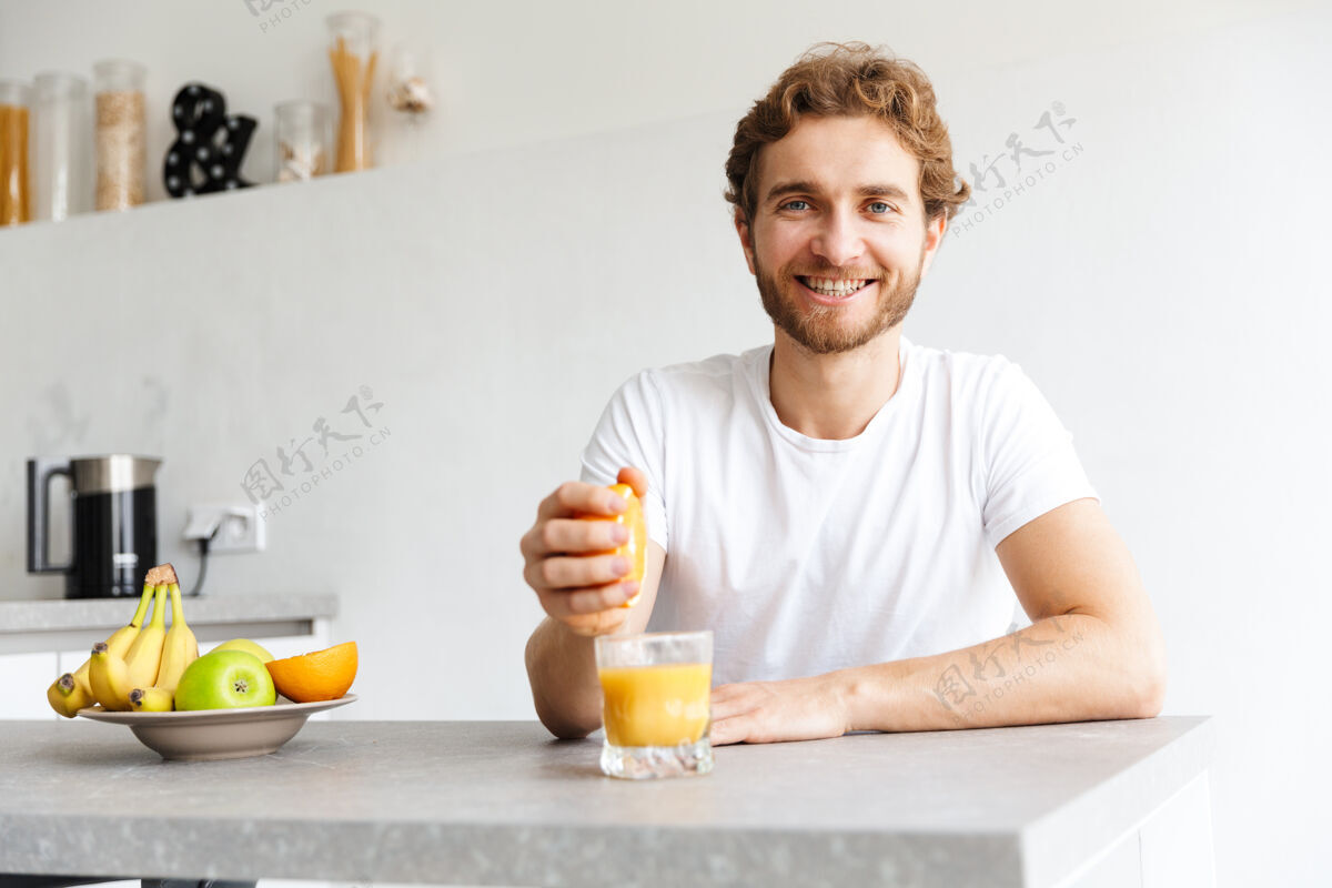 文学图为一位快乐的留着胡子的年轻人在家里用水果做果汁帅气软放松