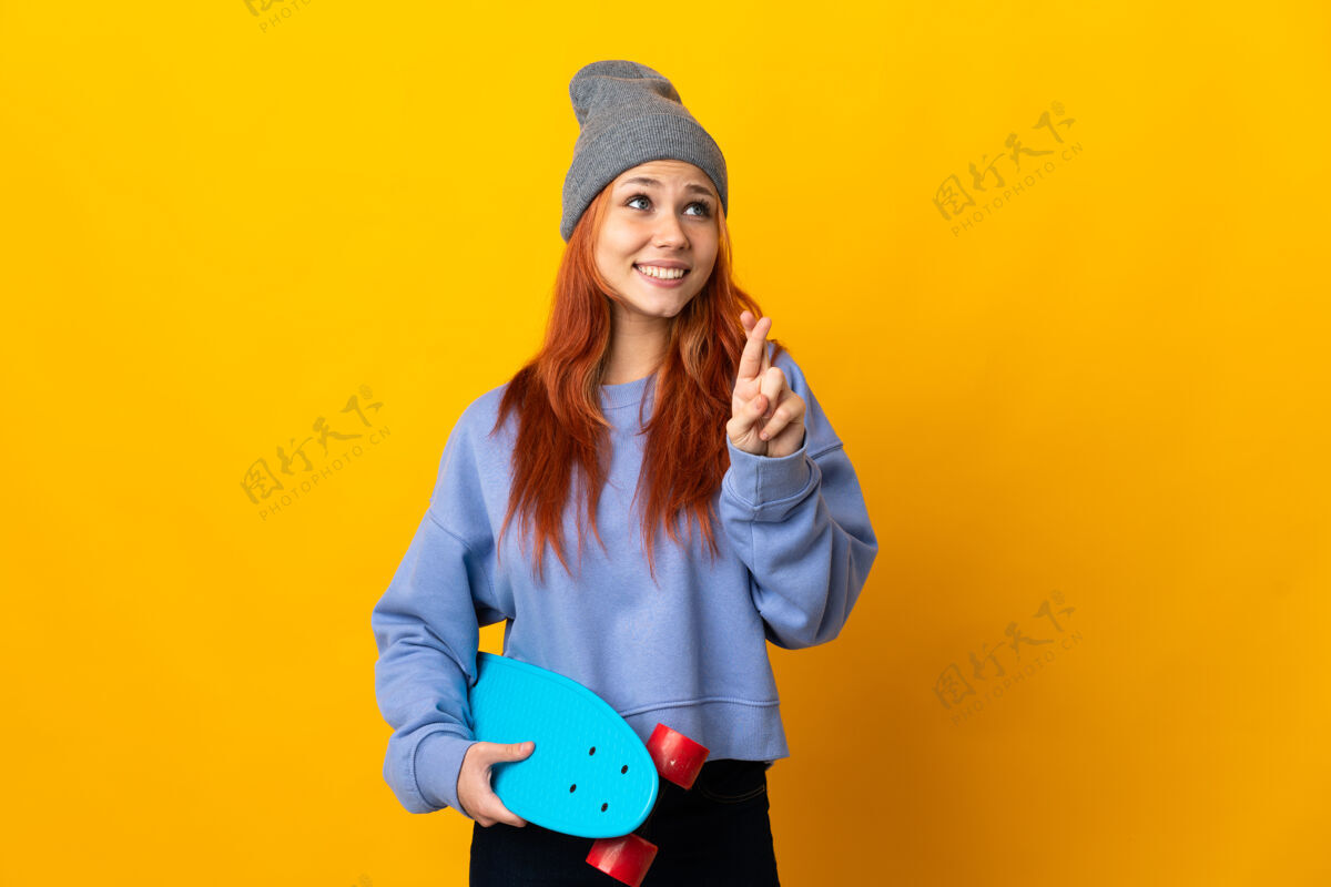 表情俄罗斯女子滑冰运动员孤立在黄色与手指交叉和祝愿最好滑板脸希望