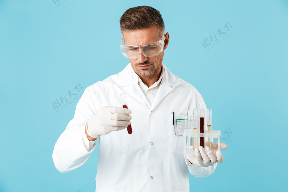 治疗一位英俊严肃的成熟男子医生在蓝色的墙上举着带血的试管摆姿势药物白种人治疗