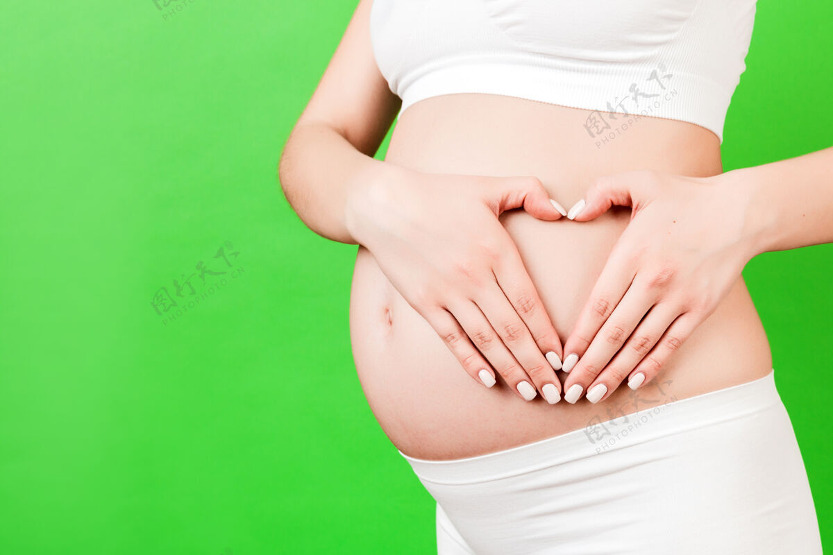 婴儿穿着白色内衣的孕妇双手呈心形孩子温柔保健