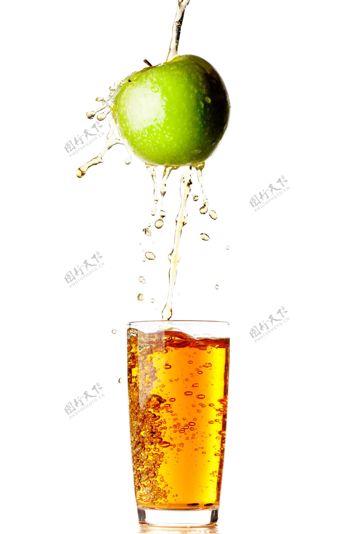 飞溅果汁从苹果倒进隔离在白墙上的玻璃里饮料配料倒