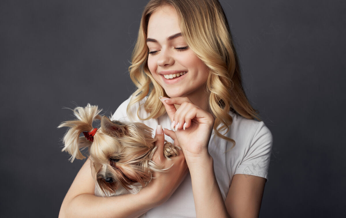 狗一个穿着白色t恤的快乐漂亮女人手里拿着一只小狗和宠物肖像衣服年轻