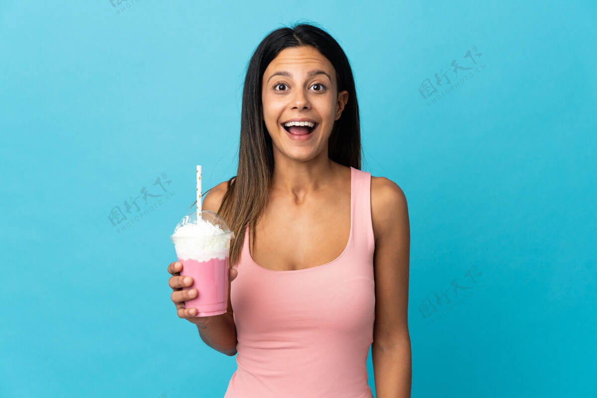 人一位年轻的女士用草莓奶昔惊讶的表情难以置信女人兴奋