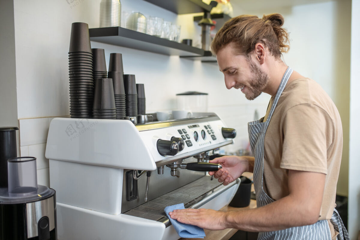 咖啡机准确年轻成人胡须微笑的男子在咖啡馆用餐巾纸擦拭咖啡机注意好看餐巾纸