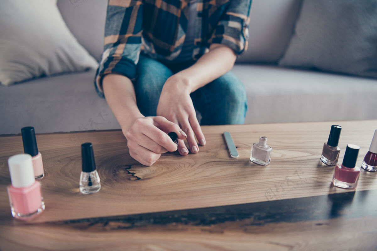 时尚裁剪特写照片的女士做了修正指甲涂上光油外套手拿在桌子上穿着休闲服坐在舒适的沙发公寓室内手指室内治疗