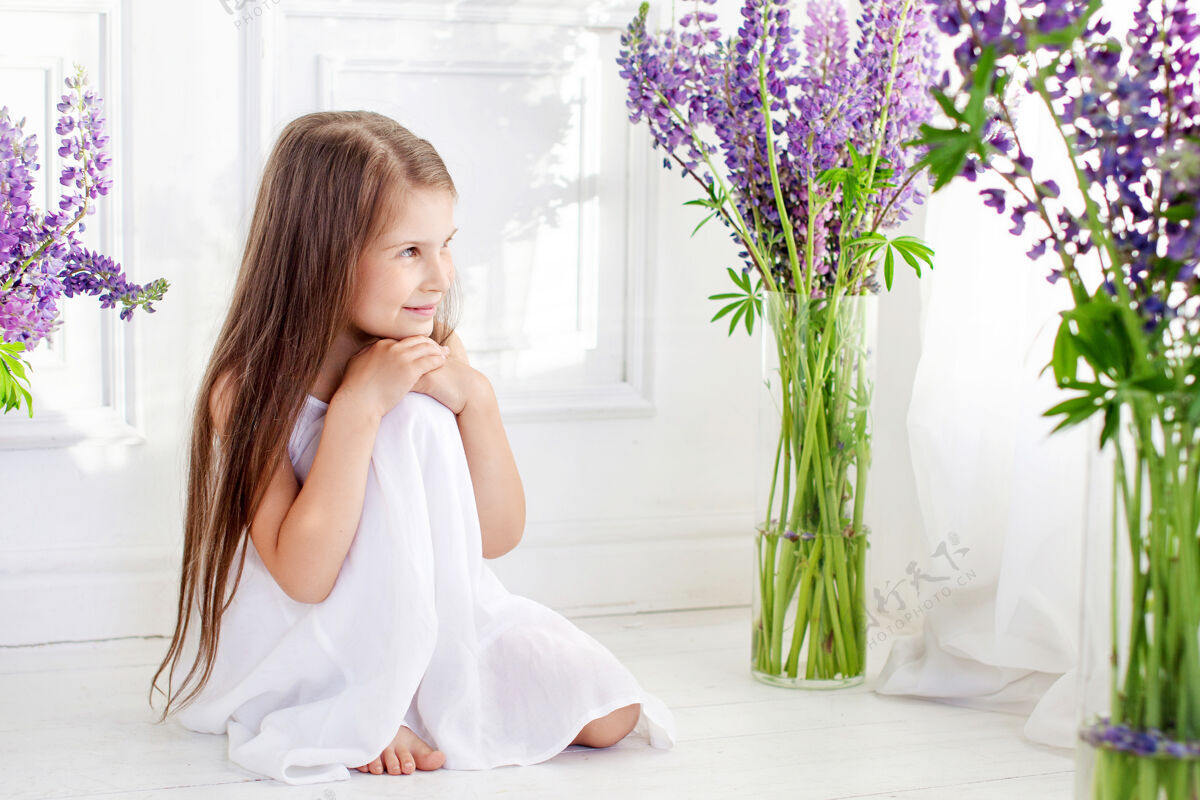 礼服美丽动情的小女孩坐在紫罗兰花丛中室内的花饰可爱花束快乐