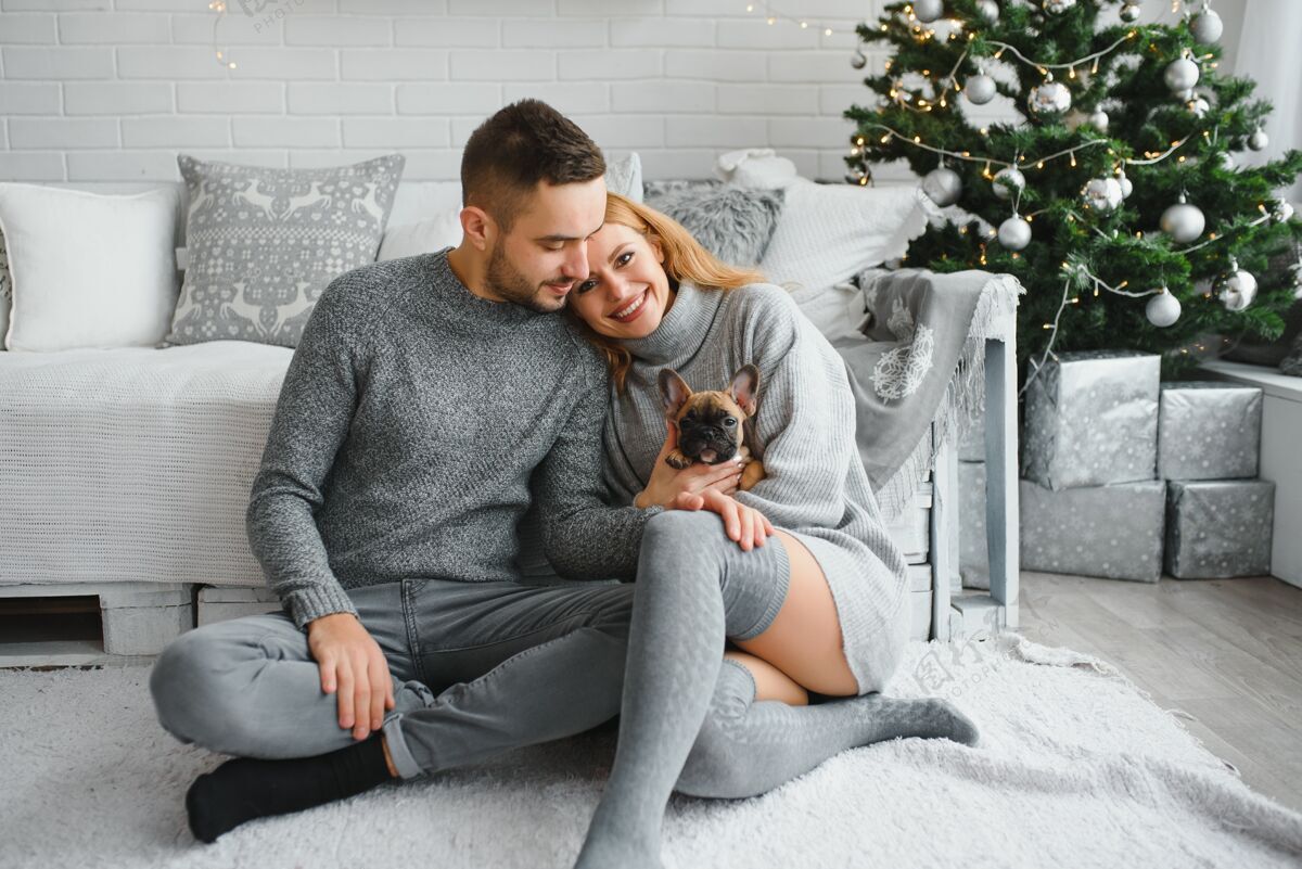 关系圣诞节前夕 一对年轻漂亮的夫妇在喜庆的新年客厅里和他们的狗玩耍在一起帅哥爱情