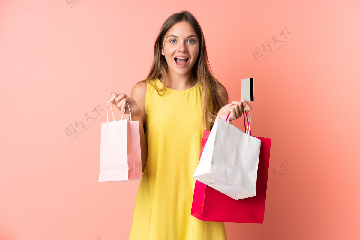 银行年轻的立陶宛女子拿着购物袋孤立在粉红色背景下 感到惊讶购物购买购物者