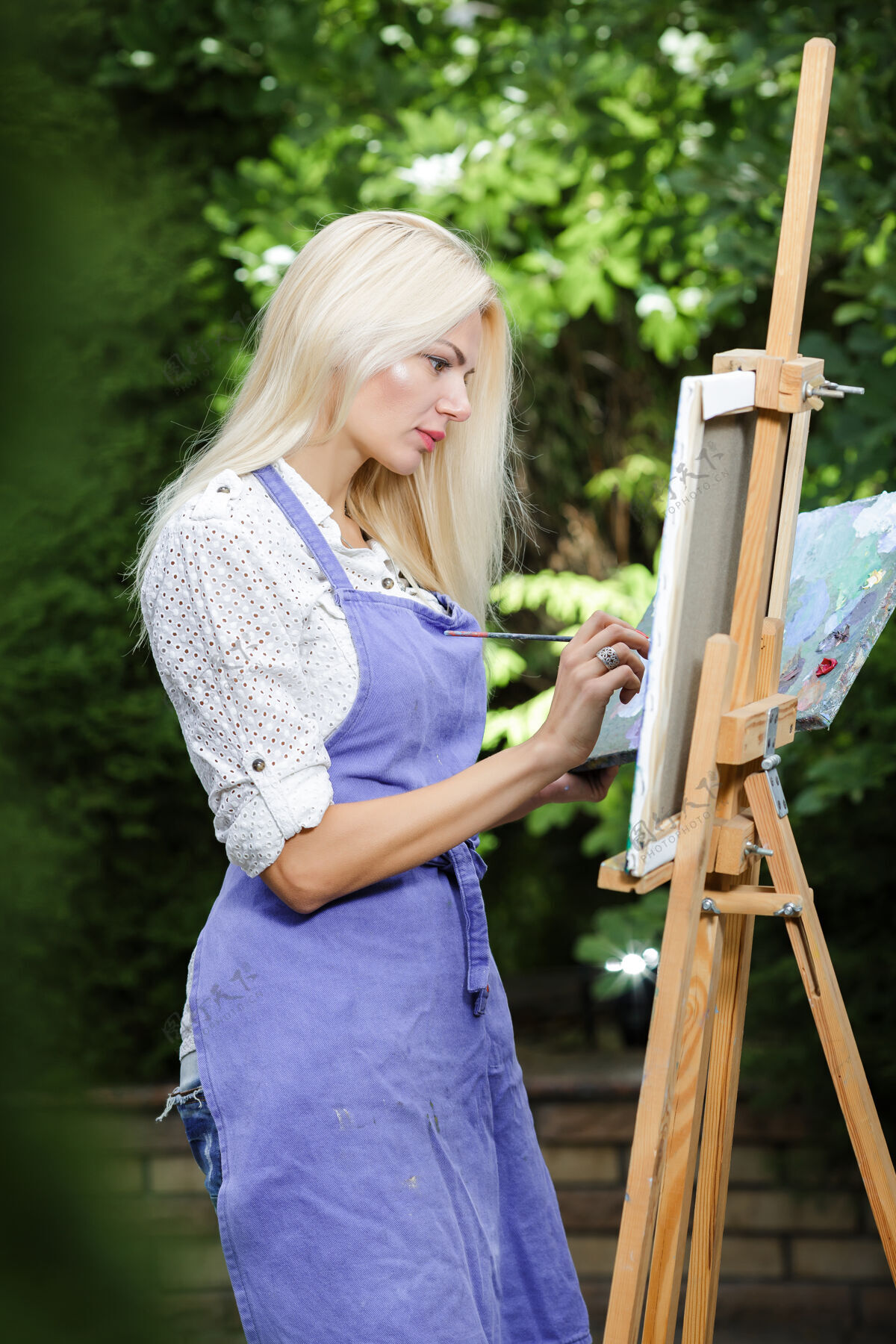 爱好美丽的金发女画家 手里拿着画笔 在大自然的画布上画画风景金发休闲