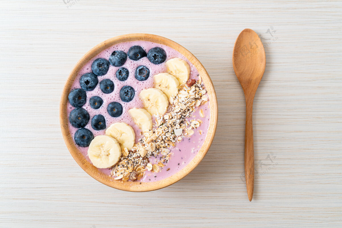 排毒酸奶或酸奶冰沙碗配蓝莓 香蕉和牛奶健康麦片美食风格紫色混合浆果